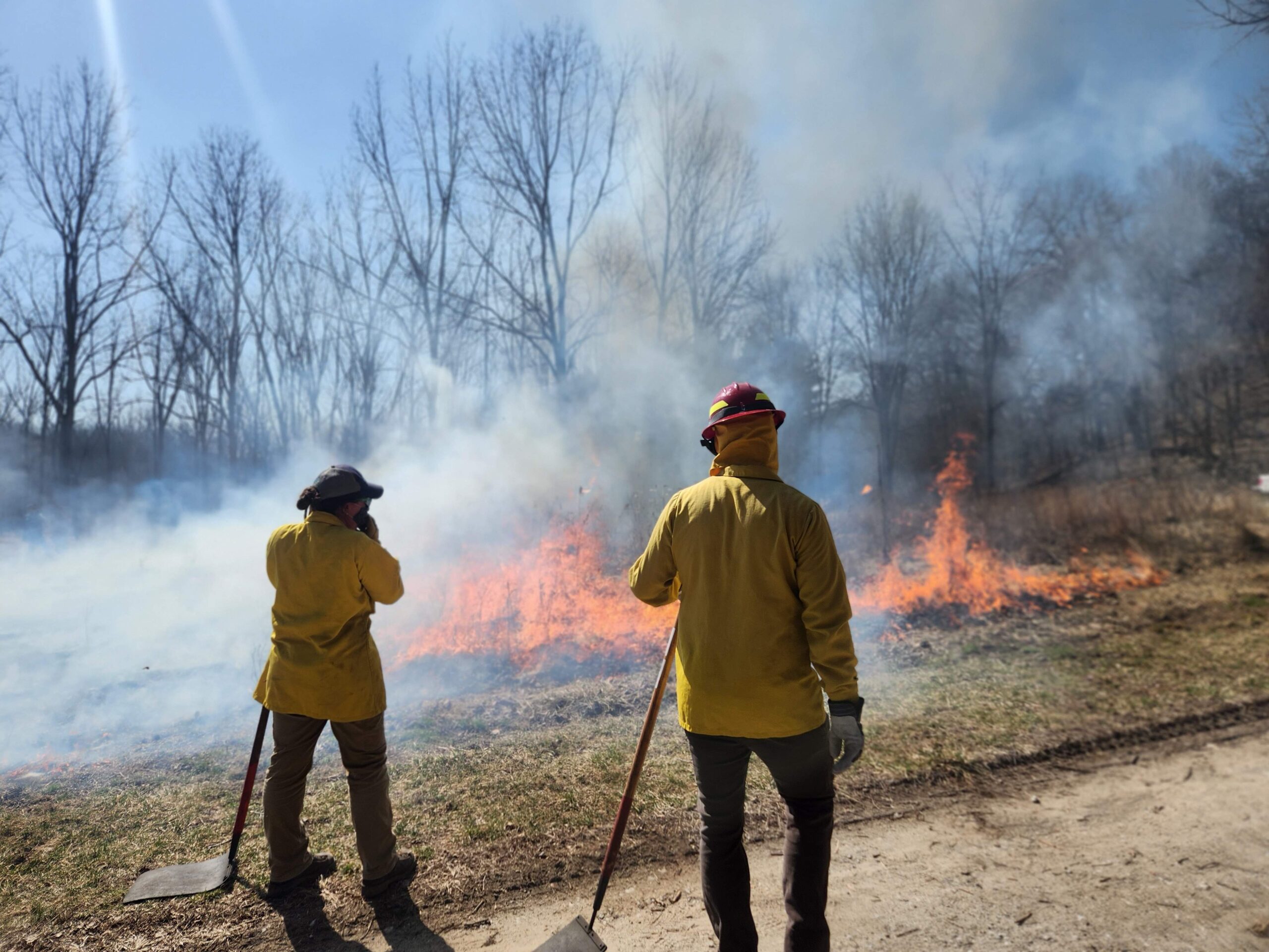 Two men standing in front of a controlled fire.